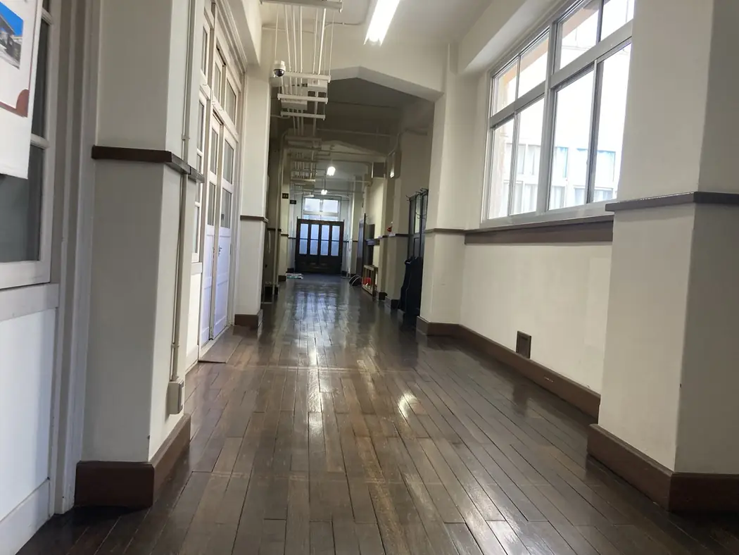 Long corridor in the former Japanese elementary school building, with wooden floors, classroom doors and tall windows