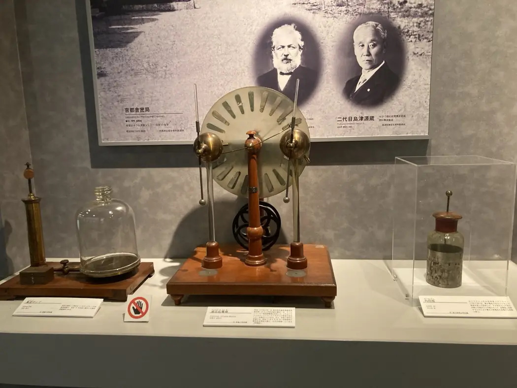 Historical electrical demonstration instruments displayed at the Kyoto Municipal Museum of School History, beneath panels about early Kyoto science teaching and Genzo Shimadzu