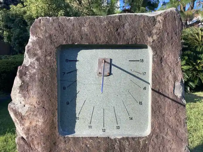 Stone sundial with hour marks and central gnomon in a landscaped outdoor area